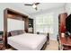Bedroom with a dark wood Murphy bed, shelving and a comfortable bed near a bright window at 12014 Belmont Mansion Dr, Charlotte, NC 28273