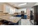 Well-lit kitchen with granite counters, stainless refrigerator, and blue painted base cabinets at 1206 Craig Ave, Lancaster, SC 29720