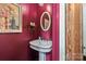 Cozy powder room featuring a pedestal sink, decorative mirror, and vibrant burgundy walls at 1801 E 8Th St, Charlotte, NC 28204