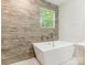 Modern bathroom featuring a freestanding tub, wood tile accent wall, and window view at 1831 Erie St, Charlotte, NC 28216