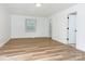 Bright room with hardwood floors, neutral paint, with a window, and door with white trim at 1831 Erie St, Charlotte, NC 28216
