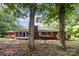 View of the backyard with a brick home, mature trees, and foliage at 215 Jan Mar Dr, China Grove, NC 28023