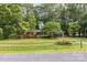 Traditional brick home with green trim surrounded by mature trees and a classic wooden fence at 215 Jan Mar Dr, China Grove, NC 28023