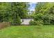 Backyard shed with white wood finish and surrounded by mature trees offering plenty of storage space at 227 Wingrave Dr, Charlotte, NC 28270
