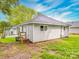 Quaint home with light gray siding and a dark roof surrounded by lush greenery at 2440 Myers St, Gastonia, NC 28056