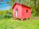 A red outbuilding or shed in a lush green backyard with a door and window at 2440 Myers St, Gastonia, NC 28056
