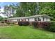 Charming single-story home with a brick accent wall and a well-manicured green lawn surrounded by lush trees at 2666 Providence Dr, Gastonia, NC 28052