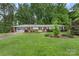 Single-story home with attached garage and well-manicured lawn, surrounded by lush trees in a peaceful setting at 2666 Providence Dr, Gastonia, NC 28052