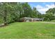 A single-story home with attached garage and well-manicured lawn, surrounded by lush trees in a peaceful setting at 2666 Providence Dr, Gastonia, NC 28052