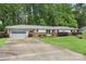 Single-story home with attached garage and well-manicured lawn, surrounded by lush trees in a peaceful setting at 2666 Providence Dr, Gastonia, NC 28052