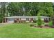 Single-story home with attached garage and well-manicured lawn, surrounded by lush trees in a peaceful setting at 2666 Providence Dr, Gastonia, NC 28052