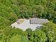 Aerial view shows building with a stone yard and surrounded by mature trees and landscaping at 364 Luther Dr, Iron Station, NC 28080