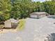 View of a large garage with multiple bays and a smaller shed, all with a stone yard at 364 Luther Dr, Iron Station, NC 28080