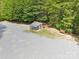 View of a shed with a stone yard bordered by a mature tree line and a wooden bench at 364 Luther Dr, Iron Station, NC 28080