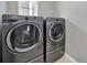 This laundry room features gray, front-loading machines and a window for natural light at 45008 Wigeon Ln # 202, Indian Land, SC 29707