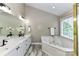 Luxurious bathroom with dual sinks, granite counters, soaking tub, and stylish fixtures at 4637 Shannamara Dr, Matthews, NC 28104