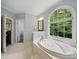 An opulent bathroom has a large arch window above a garden tub and tile floor at 550 Burrage Ne Rd, Concord, NC 28025