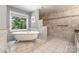 Bathroom featuring a classic clawfoot tub, a tile shower with a mosaic accent, and a large window for natural light at 6419 Antioch Ct, Matthews, NC 28104