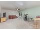 Large bonus room with a TV, a red couch, a ceiling fan, a window, and a drum set at 6419 Antioch Ct, Matthews, NC 28104