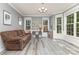 Cozy living room featuring a brown couch, wood floors, a modern chandelier, and multiple windows allowing natural light at 6419 Antioch Ct, Matthews, NC 28104