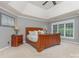 Main bedroom with a tray ceiling, a wooden bed, matching nightstands, lamps, and a window overlooking the backyard at 6419 Antioch Ct, Matthews, NC 28104