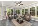 Bright sunroom with tiled floor, a ceiling fan, four chairs, a table, and multiple large windows showing the greenery outside at 6419 Antioch Ct, Matthews, NC 28104
