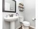 Elegant powder room featuring a pedestal sink, decorative mirror, and modern fixtures at 7414 Meridale Forest Dr, Charlotte, NC 28269