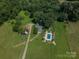 Aerial view of the property featuring an in-ground pool, outbuildings, and a serene, wooded setting at 7660 Bud Davis Rd, Vale, NC 28168