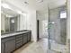 Modern bathroom featuring double vanity, granite counters, and tiled glass shower at 871 Academy St, Charlotte, NC 28205