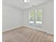 A bedroom with neutral colored walls, two windows with blinds and carpet flooring at 871 Academy St, Charlotte, NC 28205