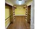 Open walk-in closet featuring wood laminate flooring and custom wood shelving for optimal storage at 8720 Lee St, Mount Pleasant, NC 28124