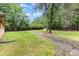 A spacious backyard with a gravel driveway, mature trees, and a small shed provides ample outdoor space at 925 Rock Grove Church Rd, Salisbury, NC 28146
