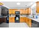 Kitchen features warm wood cabinetry, black appliances, and ample counter space at 10908 Delsing Ct, Charlotte, NC 28214