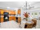 Eat-in kitchen features wood cabinetry, black appliances, and modern chandelier at 10908 Delsing Ct, Charlotte, NC 28214