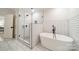 Modern bathroom with black hardware, white cabinets, a tiled shower with glass door, and a free standing tub at 1121 S Wendover Rd, Charlotte, NC 28211