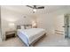 Neutral bedroom with a ceiling fan, bedside lamps on wooden nightstands, and a bed with white and gray bedding at 1121 S Wendover Rd, Charlotte, NC 28211