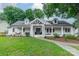 Charming white brick home boasts a covered front porch, dormer windows, and mature landscaping at 1121 S Wendover Rd, Charlotte, NC 28211