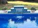 The shimmering pool showcases a charming waterfall feature, complemented by lush greenery and potted flowers at 1121 S Wendover Rd, Charlotte, NC 28211