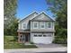 Charming two-story home featuring a light blue facade, white garage door, and a meticulously landscaped front yard at 1133 Thayer Glen Ct, Charlotte, NC 28213