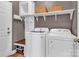Organized laundry area with white washer and dryer, shelving, and bench for convenience at 1230 Therns Ferry Dr, Fort Mill, SC 29708