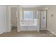 Bright bathroom featuring a bathtub with a shower, a glass block window, and a separate toilet area at 12303 Shadow Ridge Ln, Charlotte, NC 28273