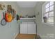 Functional laundry room with washer, dryer, shelving, and window for natural light at 12303 Shadow Ridge Ln, Charlotte, NC 28273