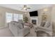 Cozy living room with a fireplace, ceiling fan, neutral color palette, and lots of natural light at 12303 Shadow Ridge Ln, Charlotte, NC 28273