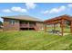 Expansive backyard showcasing a brick home with a wooden pergola, fire pit, and inviting outdoor space at 141 Tall Fern Loop, Mooresville, NC 28117
