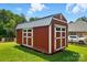 Red storage shed with white trim stands in the backyard, offering ample space for tools and equipment at 141 Tall Fern Loop, Mooresville, NC 28117