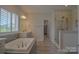 Spa-like bathroom featuring a soaking tub, walk-in shower, and abundant natural light at 15216 Shallow Ridge Rd, Charlotte, NC 28278