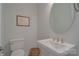 Elegant powder room with a pedestal sink, oval mirror, and toilet, offering a convenient space for guests at 15216 Shallow Ridge Rd, Charlotte, NC 28278