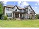 Stunning two-story home with manicured lawn and garden, stone accents, and an elegant front porch at 18745 Bluff Point Rd, Cornelius, NC 28031