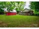 Expansive backyard with mature trees showcasing the home's exterior and red outbuilding at 224 E Steele St, Salisbury, NC 28144