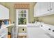 Well-lit laundry room with white cabinets, modern machines and outside view from the window at 267 Ikerd Se Dr, Concord, NC 28025